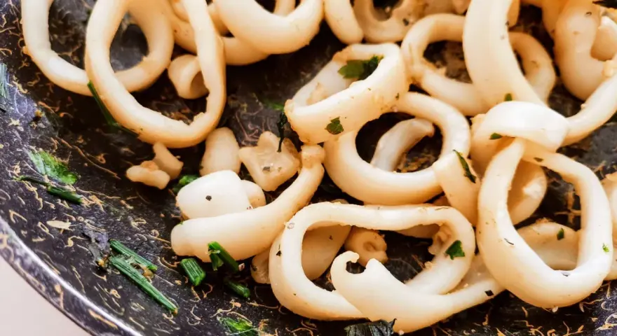 Anelli di totano in padella, dorati e profumati con erbe aromatiche, pronti per essere gustati.