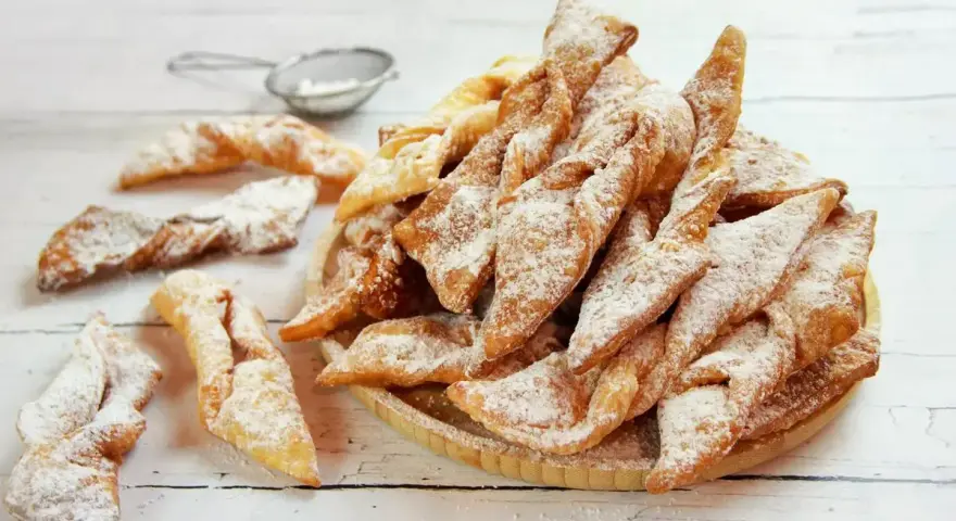 Faworki croccanti e dorati, spolverati di zucchero a velo. Un delizioso dolce da preparare seguendo un semplice faworki przepis.