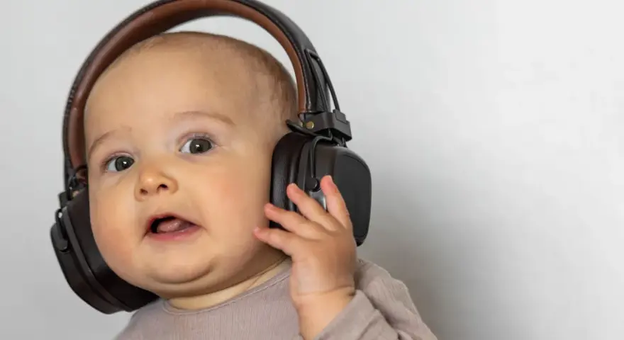 Un bébé curieux avec un casque anti-bruit. Quand utiliser un casque anti-bruit bébé à partir de quel âge ?
