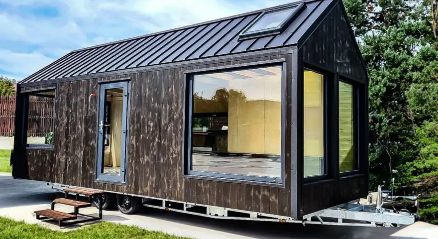 Nowoczesny tiny house w Polsce, z ciemną drewnianą elewacją i dużymi oknami, gotowy na przygodę.