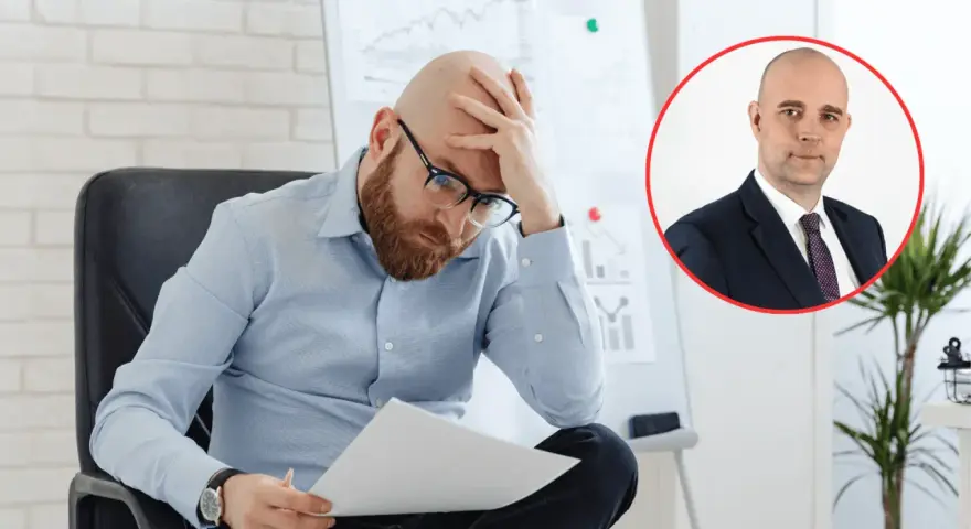 Zmartwiony mężczyzna analizuje dokumenty, podczas gdy w tle widać portret biznesmena. Obraz symbolizuje analizę przyczyn bezrobocia w Polsce.