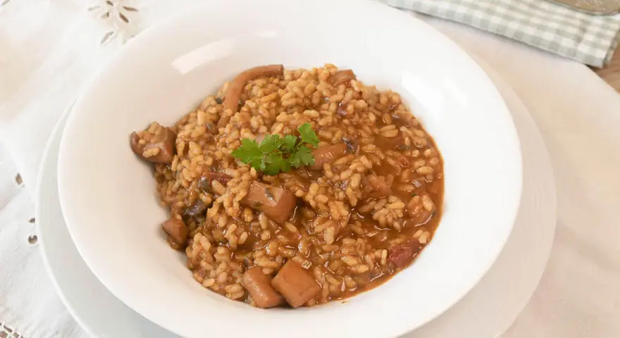Arroz con sepia en un plato blanco, decorado con perejil.