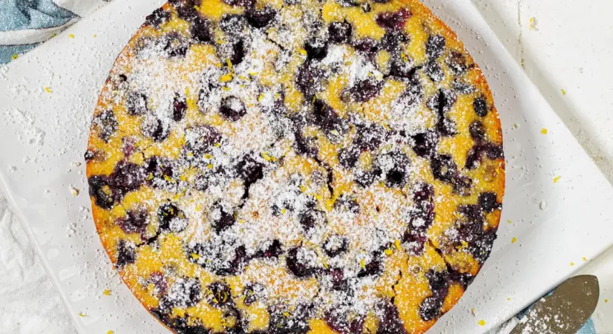 Ein köstlicher glutenfreier Kuchen mit Blaubeeren und Puderzucker bestreut, bereit zum Genießen.