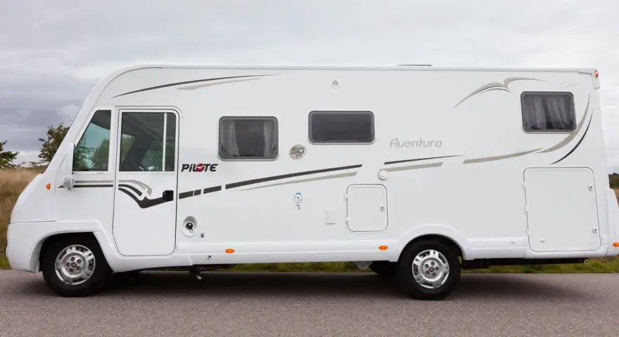 Vit husbil, Pilote G740 Aventura, parkerad vid en väg med gräs och träd i bakgrunden.