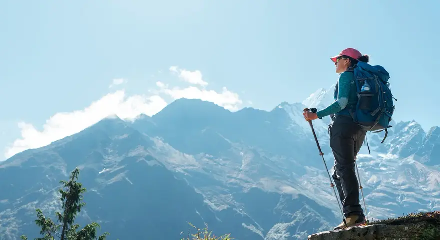 Kobieta z plecakiem i kijkami trekkingowymi podziwia majestatyczne góry podczas trekkingu pod Mount Everest.
