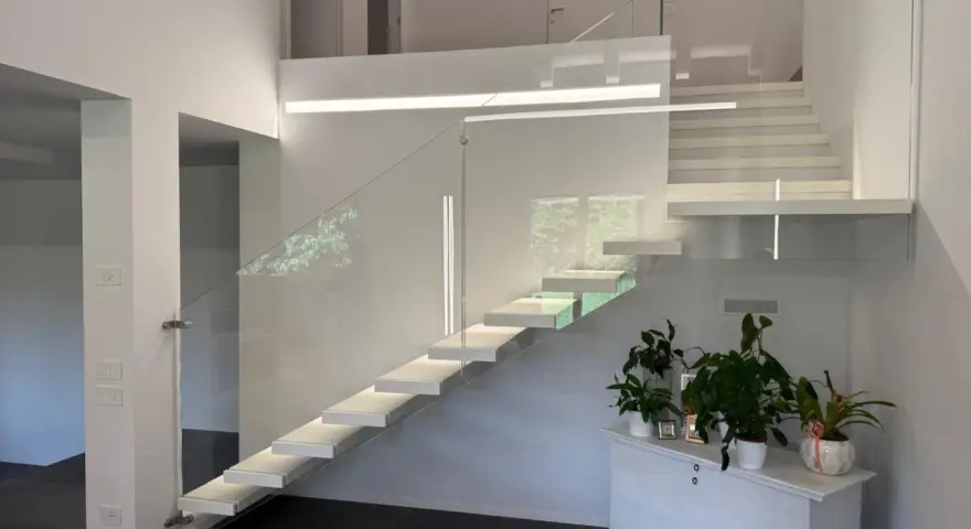 Moderna scala interna con gradini sospesi e parapetto in vetro, un esempio di come la normativa scale interne uso privato possa ispirare design eleganti e sicuri.
