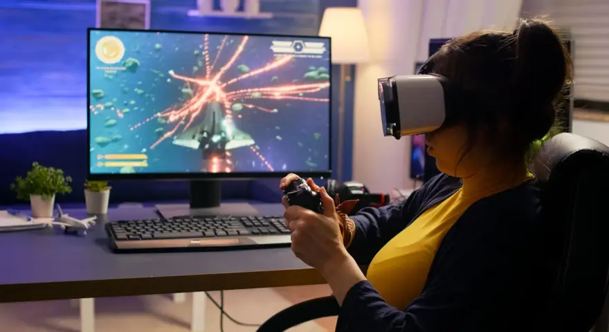 Kobieta w goglach VR gra w kosmiczną strzelankę, testując swoje umiejętności w ramach studiów game design.