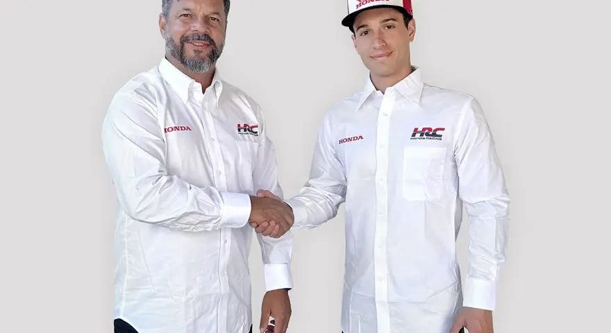 Dos hombres con camisas blancas de Honda y HRC Racing se dan la mano. Uno lleva una gorra de Honda.