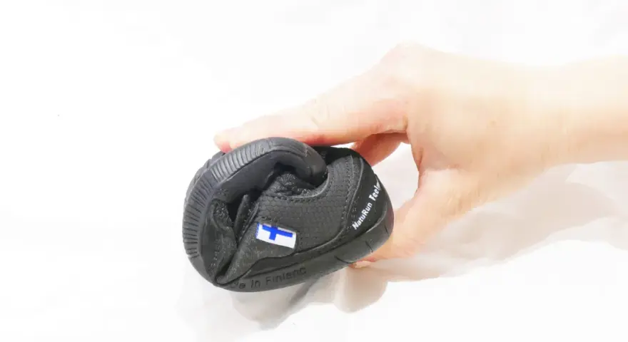 En hand håller en svart barfotasko med finska flaggan. Är barfotaskor bra eller dåligt?