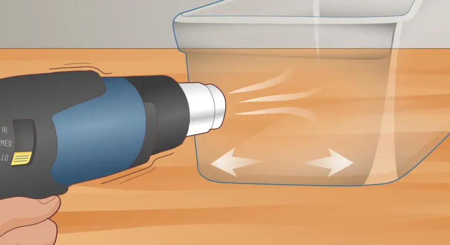 A heat gun is used on low setting to gently warm a scratched plexiglass surface, showing how to get scratches out of plexiglass.