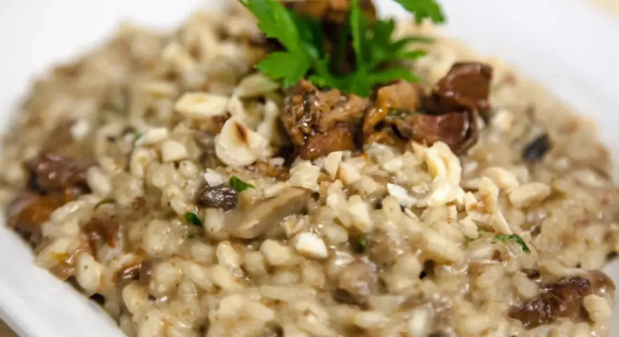 Cremoso risotto de boletus con trozos de champiñones, nueces picadas y perejil fresco.