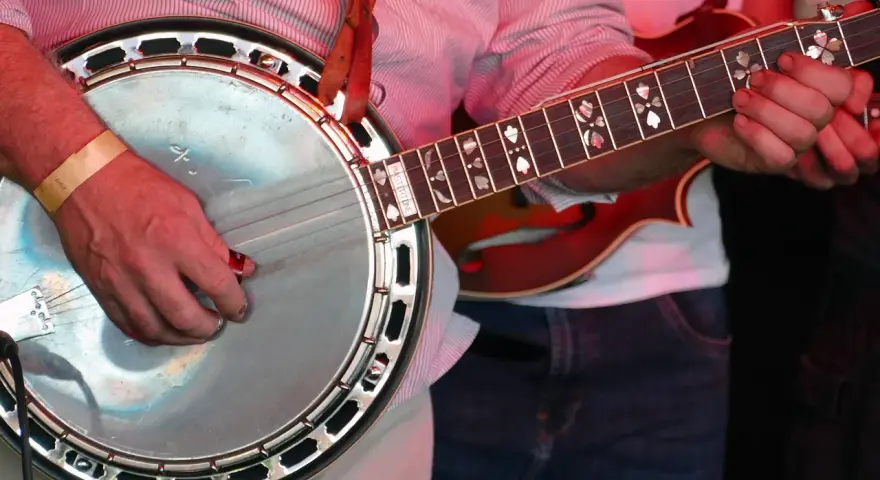 Ein Mann spielt ein Banjo, ein Saiteninstrument mit einem runden Korpus und einem langen Hals.