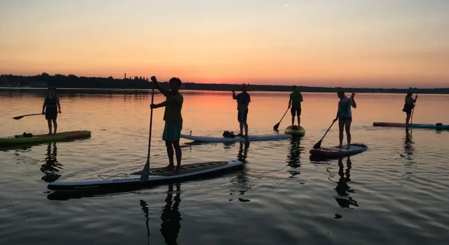 Sonnenuntergang über Berlin: Eine Gruppe genießt Wassersport auf Stand-Up-Paddle-Boards.