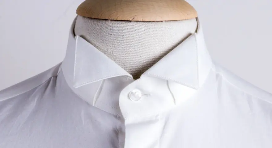 Dettaglio di una camicia bianca su un manichino, che mostra i diversi tipi di colletto camicia.