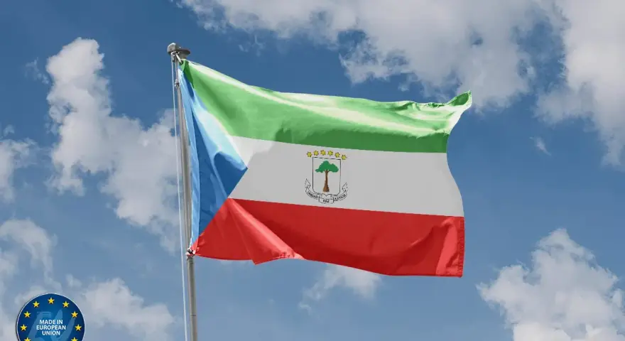 Flaga Gwinei Równikowej powiewa na tle błękitnego nieba z chmurami. Symbolizuje jedność, pokój i sprawiedliwość.