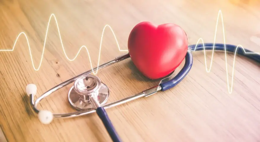 Czerwone serce i stetoskop na drewnianym tle z linią EKG.