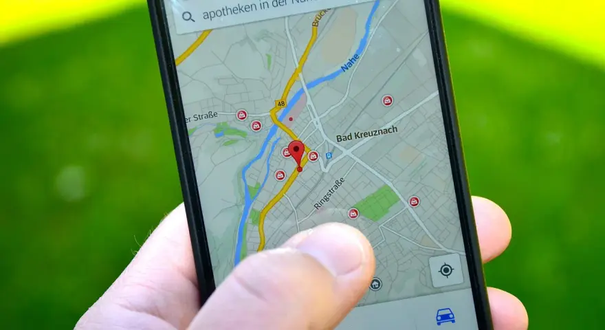 Palec wskazuje na mapę GPS w telefonie, szukając apteki w pobliżu. W samochodzie taka nawigacja to podstawa.
