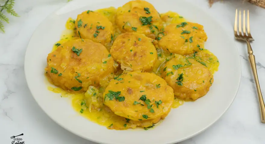 Patatas a la importancia, doradas y tiernas, bañadas en una salsa amarilla con perejil picado. Un plato que demuestra la importancia de las patatas en la cocina.