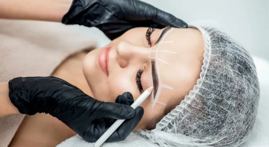 Stylist rysuje kredką idealny kształt brwi przed zabiegiem henny. Dowiedz się, ile trwa henna brwi i jak przygotować się do zabiegu.