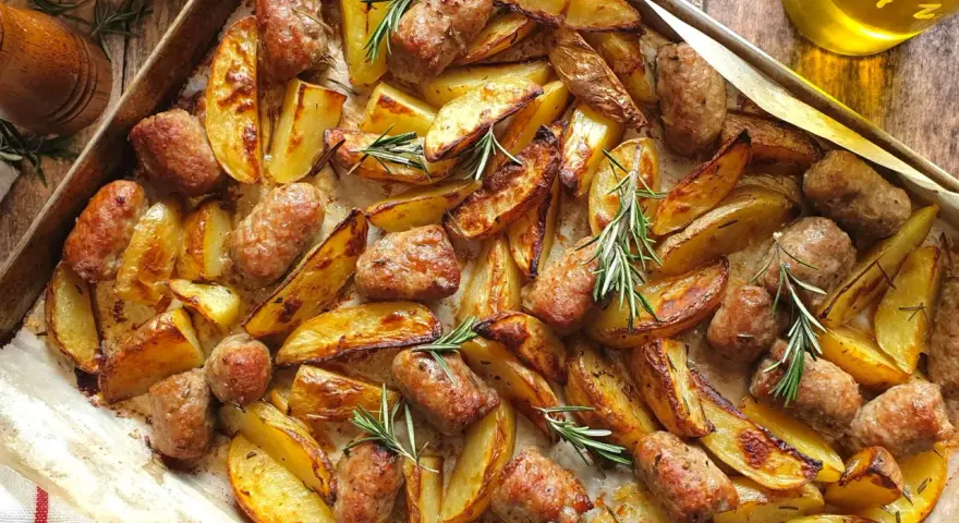 Salsiccia e patate al forno, dorate e profumate al rosmarino, pronte per essere gustate.