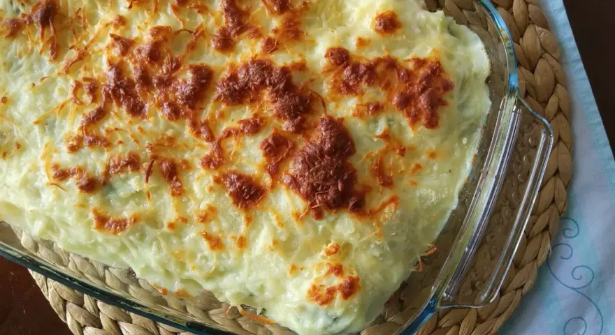 Parmentier de patata gratinado en fuente de cristal, con queso dorado y burbujeante. Un plato reconfortante y delicioso.