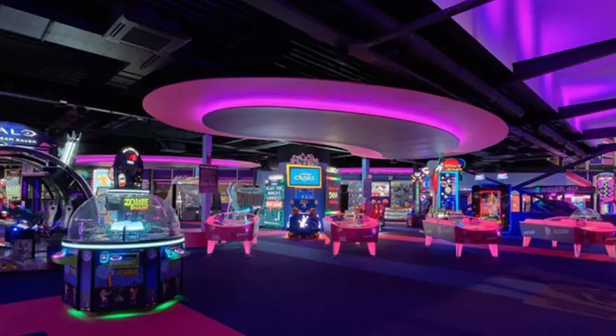 Bunte Spielautomaten und Air-Hockey-Tische in einem beleuchteten Gamestate Potsdamer Platz.