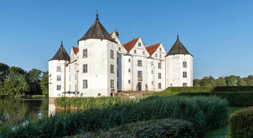 Wasserschloss in Schleswig-Holstein, ideal für die herbstferien 2025. Ein malerisches Schloss mit Türmen und Wassergraben.