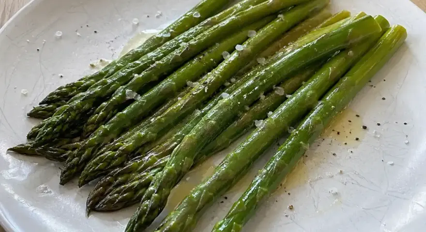 En tallrik med nykokt sparris, lätt oljad och strödd med flingsalt och peppar. Perfekt för att koka sparris till en enkel och god rätt.