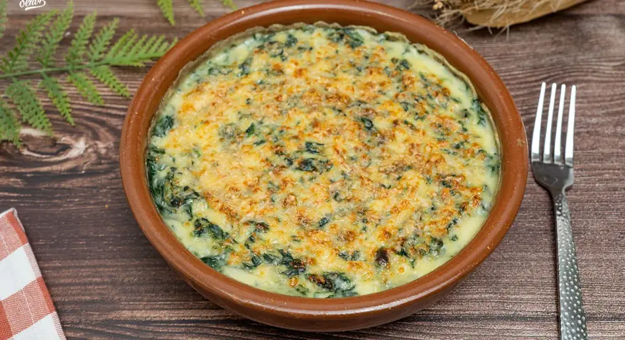 Delicioso plato de espinacas a la crema gratinadas con queso, servido en cazuela de barro. Un bocado cremoso y reconfortante.