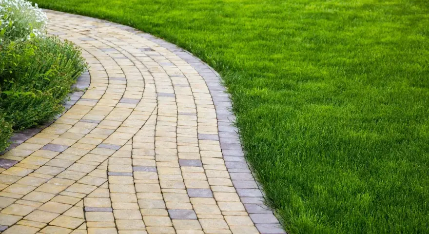Vialetti giardino fai da te in pietra, con prato verde curato e aiuole fiorite.