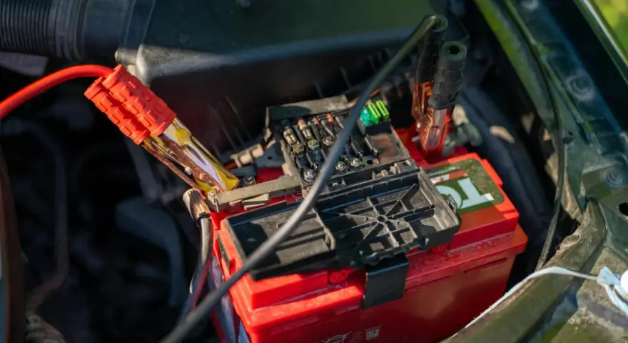 Jump starter cables connected to a car battery. This shows how a jump starter can charge a battery to get your car running again.