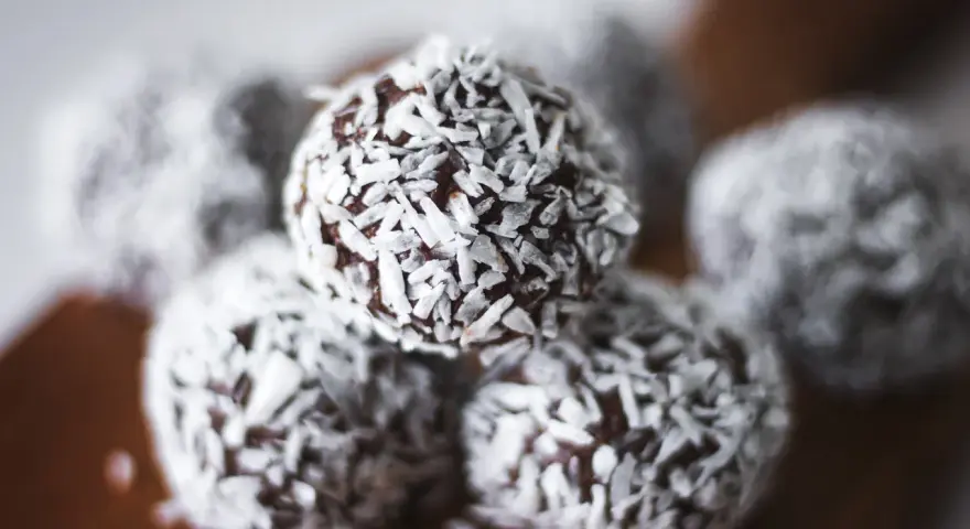 Nära bild på protein chokladbollar täckta med kokosflingor. Perfekt för ett snabbt mellanmål.