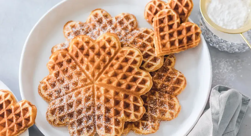 Herzförmige Waffeln mit Puderzucker bestäubt, ein Genuss für Kinder.