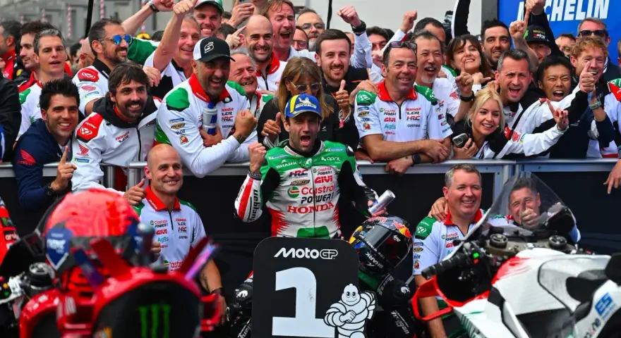 El equipo celebra un podio en el calendario MotoGP. El piloto número 1, rodeado de su equipo, muestra su alegría.