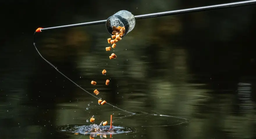 Karmnik method feeder wysypuje zanętę do wody, tworząc chmurę przynęty dla ryb.