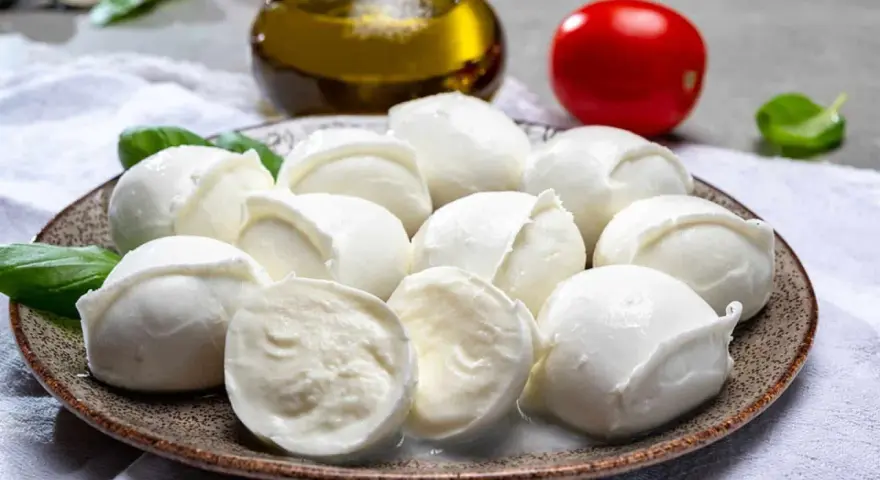 Frische Mozzarellakugeln auf einem Teller, garniert mit Basilikum. Perfekt für eine leichte Mahlzeit während der Schwangerschaft.