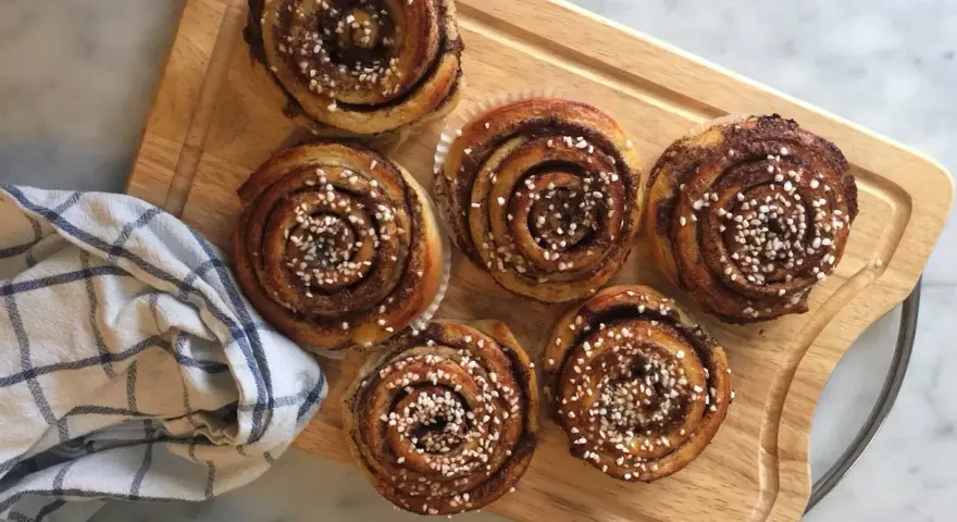 Sju gyllene kanelbullar med pärlsocker, redo att avnjutas. En härlig påminnelse om hur bakar man.