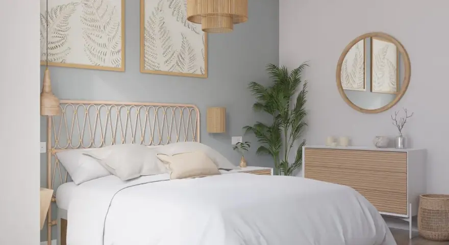 Dormitorio con paredes en colores pastel, cama blanca, cabecero de ratán y cuadros de helechos.