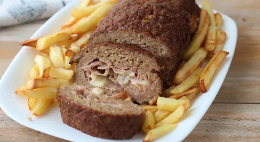 Polpettone ripieno di prosciutto e formaggio, cotto in friggitrice ad aria, servito con patatine fritte croccanti.