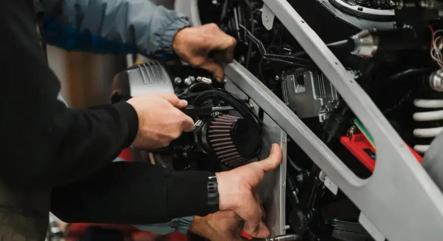 Mechanicy montują nowy filtr powietrza w motocyklu. Zepsuty filtr powietrza objawy to m.in. spadek mocy.