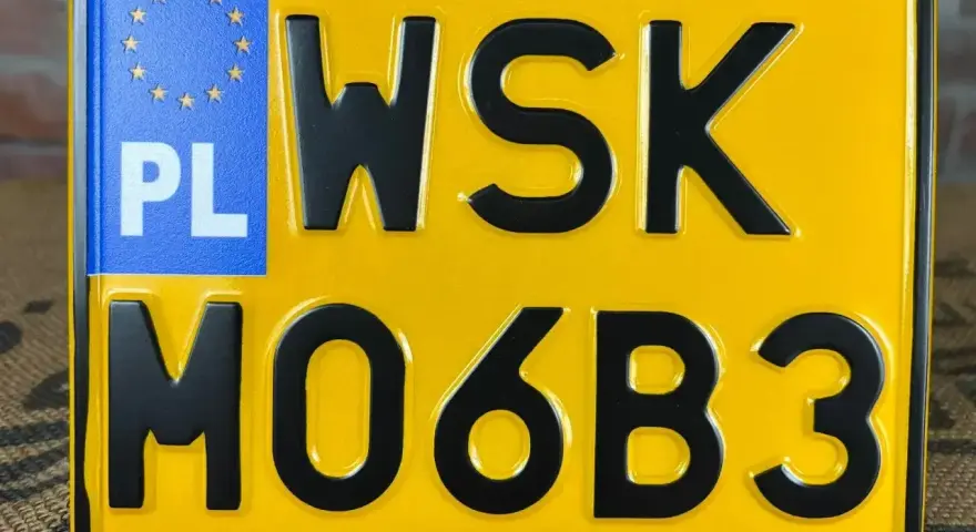 Żółta tablica rejestracyjna z czarnymi znakami "WSK MO6B3" i niebieskim polem "PL" z gwiazdkami UE.