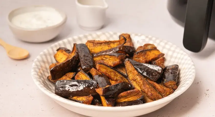 Berenjenas en freidora de aire, doradas y crujientes, listas para disfrutar con un dip cremoso.