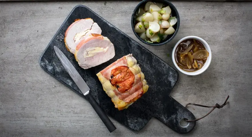 Un délicieux roti de porc Orloff, tranché et garni, accompagné de légumes et d'une sauce onctueuse.