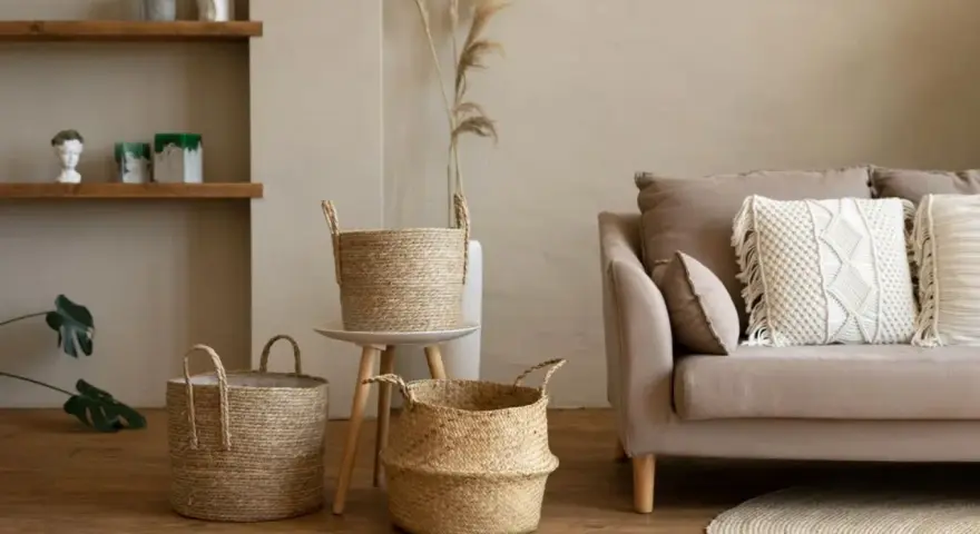 Przytulny salon w stylu boho: plecione kosze, beżowa kanapa z makramową poduszką i suszone trawy.