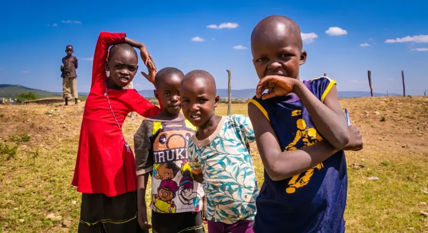 Dzieci z plemienia Masajów, żyjących w Kenii i Tanzanii, pozują do zdjęcia na tle sawanny.