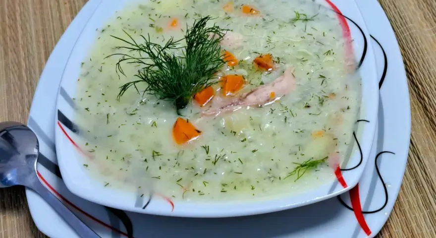 Aromatyczna zupa koperkowa z ryżem, kawałkami kurczaka i marchewką, udekorowana gałązką koperku.