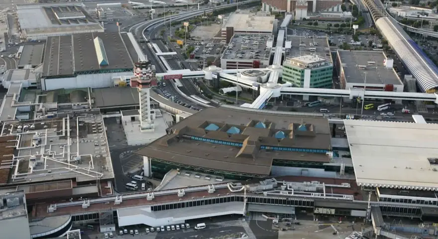 Widok z lotu ptaka na lotnisko Rzym Fiumicino z wieżą kontroli lotów, terminalami i drogami.