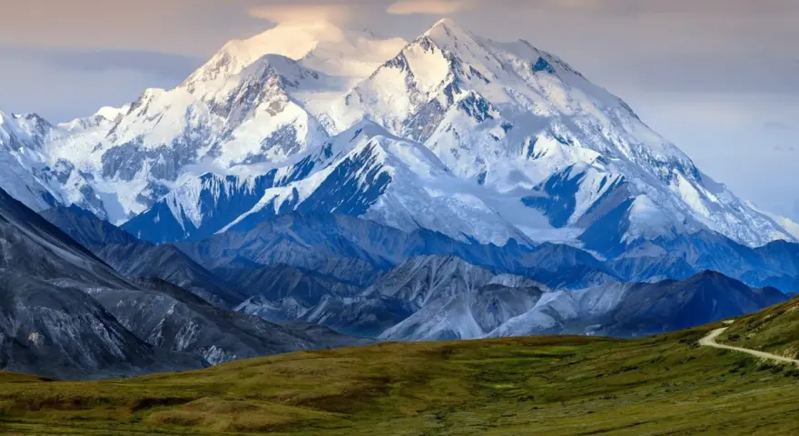 Majestatyczny, ośnieżony szczyt Denali, jednego z najwyższych szczytów kontynentów, góruje nad surowym krajobrazem.