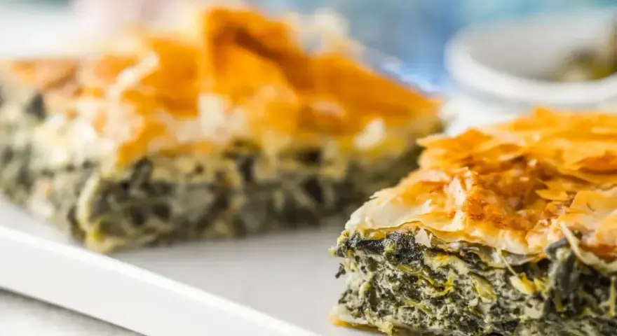 Chrupiąca spanakopita z warstwami ciasta filo i zielonym nadzieniem ze szpinaku i sera.