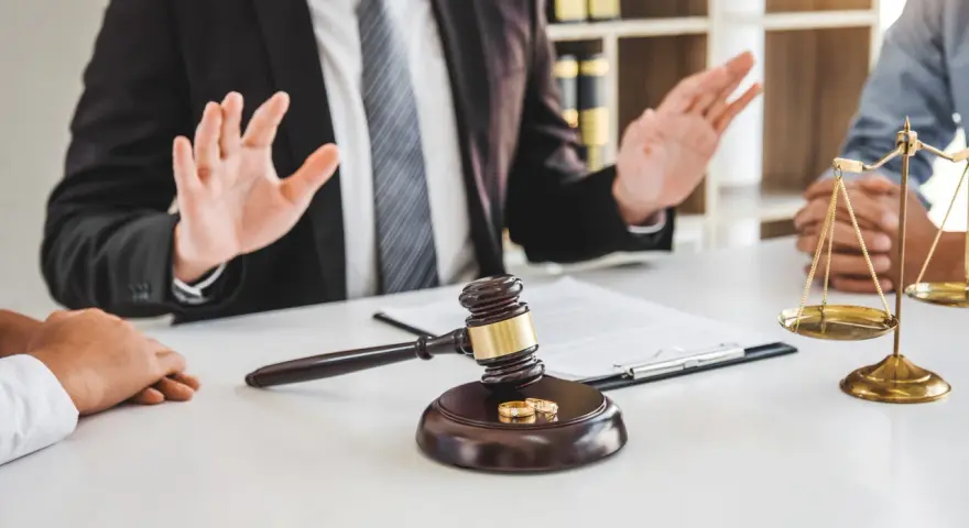 Un avocat explique les démarches pour un papier divorce mairie. Marteau de juge, alliances et balance de la justice sur la table.